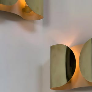 Inspired by iconic mid-century Italian design, the Foglio Wall Sconce brings refined elegance and architectural presence to any interior. Crafted from solid brass with a luxurious Italian gold finish, this sculptural sconce evokes the graceful fold of paper—its name, Foglio, meaning “sheet” in Italian.