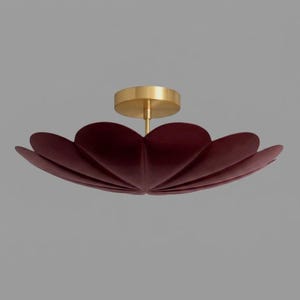 May include: A flush mount ceiling light fixture featuring a deep burgundy, velvet-textured shade shaped like a wide, multi-petaled flower. The central mounting canopy is finished in a brushed brass tone, connecting to the center of the shade.