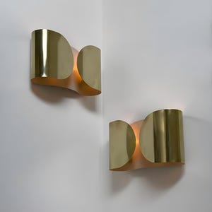 Inspired by iconic mid-century Italian design, the Foglio Wall Sconce brings refined elegance and architectural presence to any interior. Crafted from solid brass with a luxurious Italian gold finish, this sculptural sconce evokes the graceful fold of paper—its name, Foglio, meaning “sheet” in Italian.