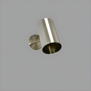 Bring timeless elegance to your interior with this handcrafted Mid-Century Brass Wall Sconce. Inspired by 1950s design, it features clean lines, a satin nickel finish, and soft ambient lighting—perfect for bedrooms, hallways, or reading nooks. Made from solid brass and built to last, this sconce blends vintage charm with modern craftsmanship. Hardwired with E12/E14 socket. Bulb not included.