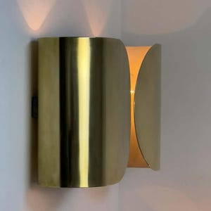 Inspired by iconic mid-century Italian design, the Foglio Wall Sconce brings refined elegance and architectural presence to any interior. Crafted from solid brass with a luxurious Italian gold finish, this sculptural sconce evokes the graceful fold of paper—its name, Foglio, meaning “sheet” in Italian.