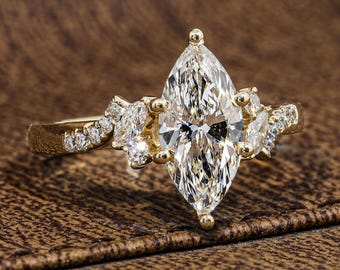 May include: A gold ring featuring a large marquise-cut center stone flanked by smaller marquise and round-cut accent stones. The band is crafted from polished yellow gold and is set with a series of tiny, sparkling round diamonds along the shoulders.