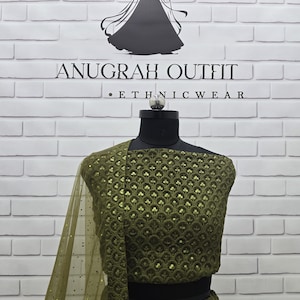 May include: Olive green ethnic wear ensemble on a mannequin. The outfit features intricate sequin detailing and a sheer, matching dupatta. The background includes the text "ANUGRAH OUTFIT &bull; ETHNICWEAR" and a silhouette of a woman.