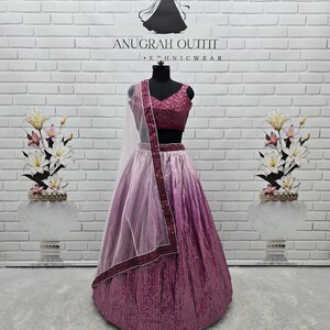 May include: A formal magenta and pink sequined lehenga choli set on a mannequin. The set includes a sequined top, skirt, and a sheer dupatta with a magenta border. The background features a white brick wall with the text "ANUGRAH OUTFIT - ETHNICWEAR".