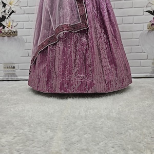 May include: A formal gown in shades of purple, with a sequined skirt and a sheer, light purple shawl. The shawl is trimmed with a dark purple border. The gown is likely for a special occasion.