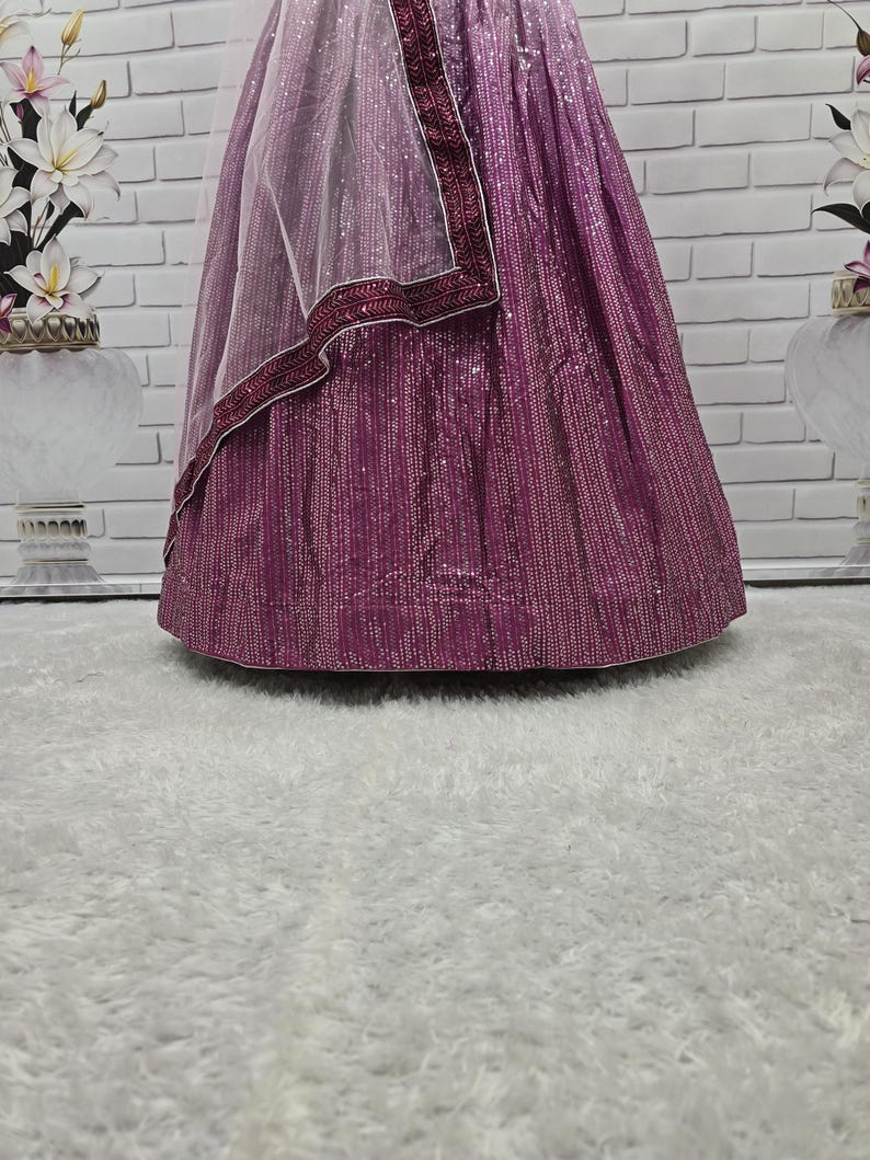 May include: A formal gown in shades of purple, with a sequined skirt and a sheer, light purple shawl. The shawl is trimmed with a dark purple border. The gown is likely for a special occasion.