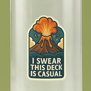 May include: A clear water bottle with a blue cap and a sticker featuring a volcano erupting with orange and yellow lava. The sticker has the text "I SWEAR THIS DECK IS CASUAL" in white letters on a green background.