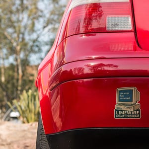 May include: Close-up of a red car's rear bumper with a sticker. The sticker features a retro computer graphic with the text "An error has occurred." Below, it reads "LIMEWIRE LOYALTY PROGRAM."