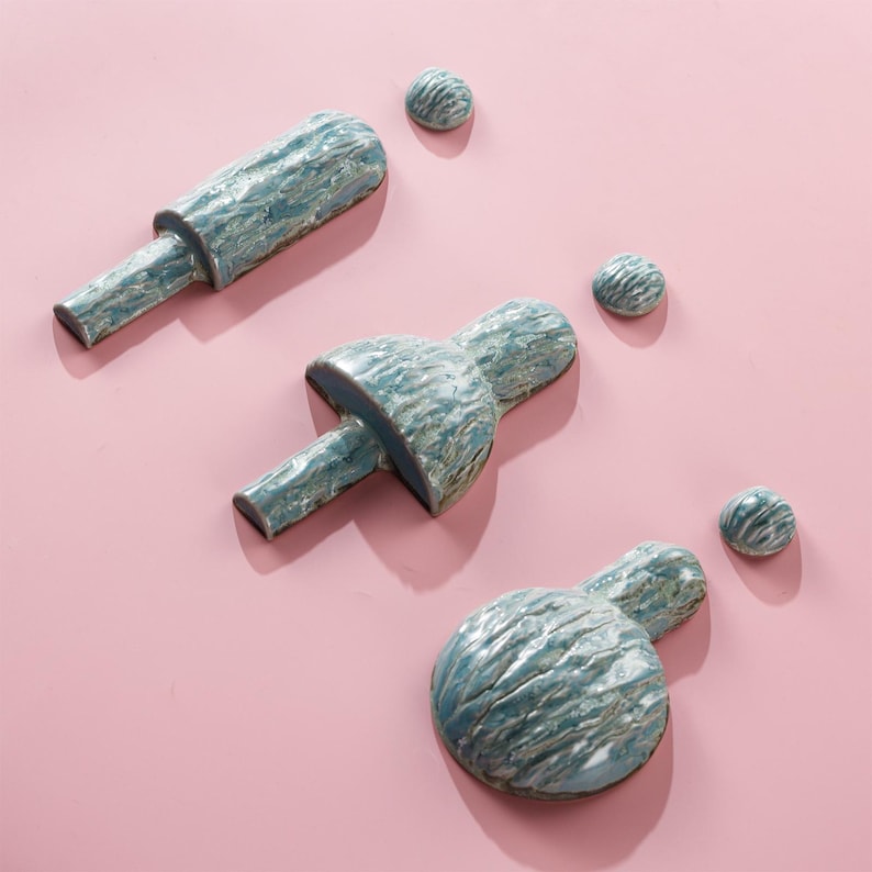 以下が含まれることがあります： ピンク色の背景に配置された、青と白の色合いの職人技のセラミック彫刻。 セットには、3 つの抽象的な形と 3 つの小さな球が含まれています。 テクスチャ加工された表面とユニークな形状は、モダンアートの美学を示唆しています。 寸法はcmです。