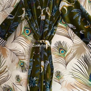 May include: Olive green velvet robe with a jungle print featuring leopards, zebras, and toucans. The robe has a striped collar and cuffs, and a matching belt. The text "Zooeyhandmade" is visible on the robe.