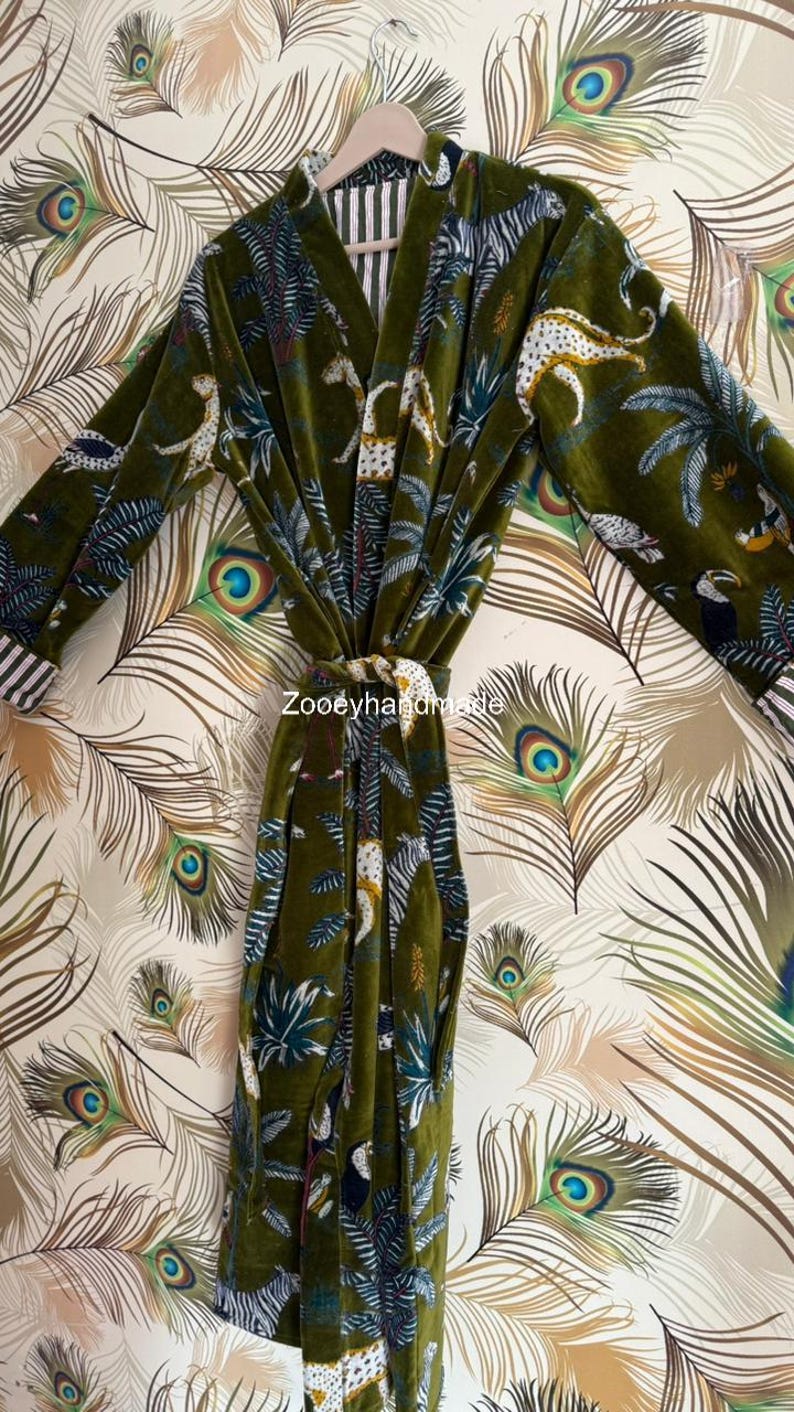 May include: Olive green velvet robe with a jungle print featuring leopards, zebras, and toucans. The robe has a striped collar and cuffs, and a matching belt. The text "Zooeyhandmade" is visible on the robe.