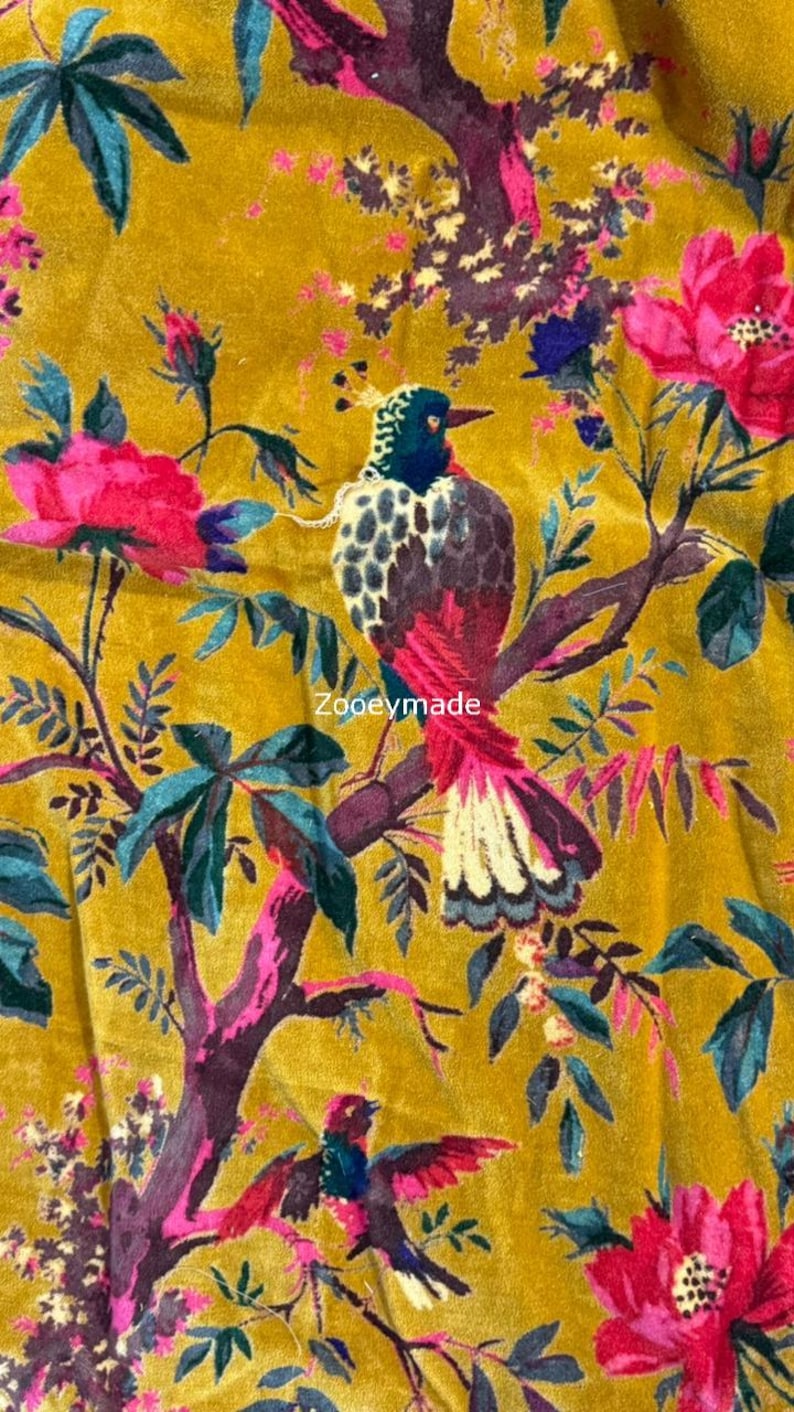 May include: Mustard yellow fabric with a floral and bird design. The fabric features a bird with a red tail and a black and white spotted back, perched on a branch. Pink flowers and teal leaves are also present.