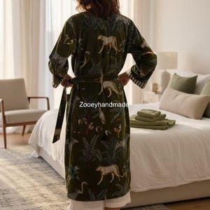 May include: Olive green robe with a jungle and leopard print. The robe has a matching belt and white trim on the sleeves. The text "Zooeyhandmade" is visible on the robe.