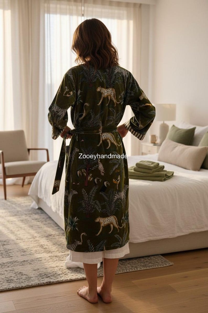 May include: Olive green robe with a jungle and leopard print. The robe has a matching belt and white trim on the sleeves. The text "Zooeyhandmade" is visible on the robe.