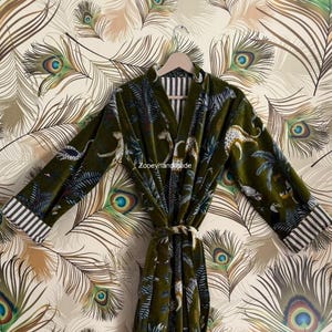 May include: A green velvet robe with a jungle print featuring leopards and palm trees. The robe has a striped collar and cuffs, and a matching belt. The text "Zooeyhandmade" is visible on the robe.