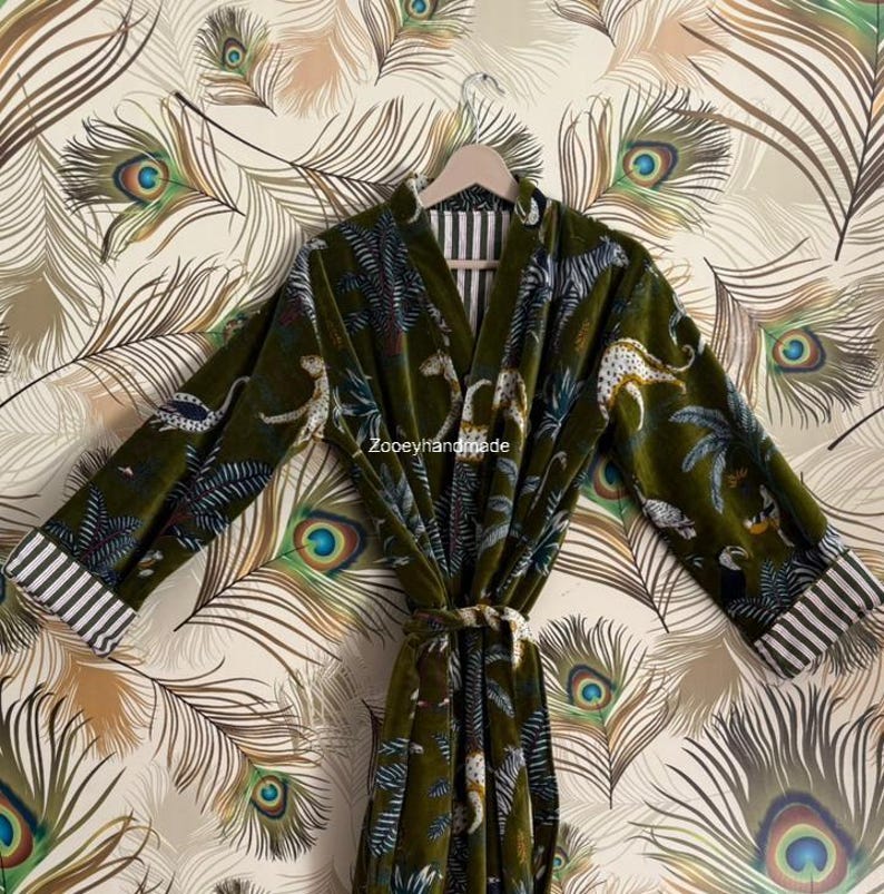 May include: A green velvet robe with a jungle print featuring leopards and palm trees. The robe has a striped collar and cuffs, and a matching belt. The text "Zooeyhandmade" is visible on the robe.