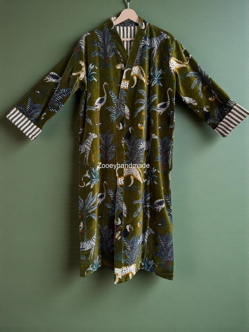 May include: Olive green velvet robe with a jungle animal print featuring zebras, leopards, and birds. The robe has a V-neck and striped cuffs. The text "Zooeyhandmade" is visible on the robe.