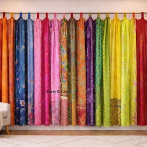 May include: A vibrant array of colorful curtains hangs from a rod, showcasing a spectrum of hues including orange, blue, pink, and green. The curtains are made of patterned fabric, adding texture and visual interest to the room. A white armchair and a potted plant are in the foreground.