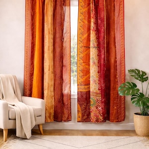 Könnte beinhalten: Mehrfarbige Vorhänge in Orange-, Rot- und Gelbtönen hängen an einer dunkelroten Stange. Die Vorhänge haben ein Patchwork-Design mit floralen und geometrischen Mustern. Ein weißer Stuhl und eine Topfpflanze befinden sich im Vordergrund.