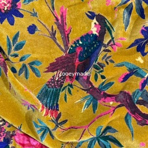 May include: Mustard yellow fabric with a vibrant floral and bird pattern. The design features colorful birds perched on branches with pink flowers and teal leaves. The text "Zooeymade" is visible on the fabric.