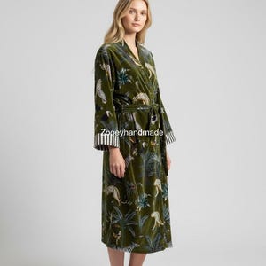 May include: Olive green velvet robe with a jungle and leopard print. The robe has a wrap-around design with a matching belt. The sleeves have a striped cuff. The text "Zooeyhandmade" is printed on the robe.