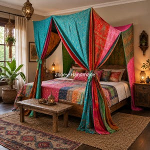 Op de afbeelding: Een hemelbed-overkapping gemaakt van levendige, veelkleurige patchworkstof met ingewikkelde bloemmotieven in tinten turquoise, rood, roze en oranje. De overkapping hangt over een houten bedframe met een bijpassende patchworksprei en kussens.