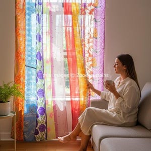 Op de afbeelding: Kleurrijke patchwork gordijnen met diverse patronen en kleuren, waaronder oranje, blauw, paars en rood. De gordijnen hangen voor een raam, met de tekst "this images © Zooeycurtains" zichtbaar.