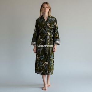 May include: A long, olive green robe with a jungle-themed pattern featuring leopards and foliage. The robe has a belt, pockets, and striped cuffs. The text "Zooeyhandmade" is visible on the robe.