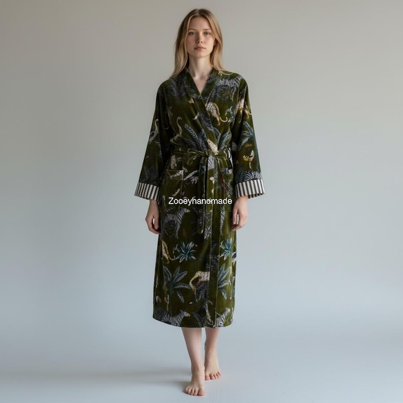 May include: A long, olive green robe with a jungle-themed pattern featuring leopards and foliage. The robe has a belt, pockets, and striped cuffs. The text "Zooeyhandmade" is visible on the robe.