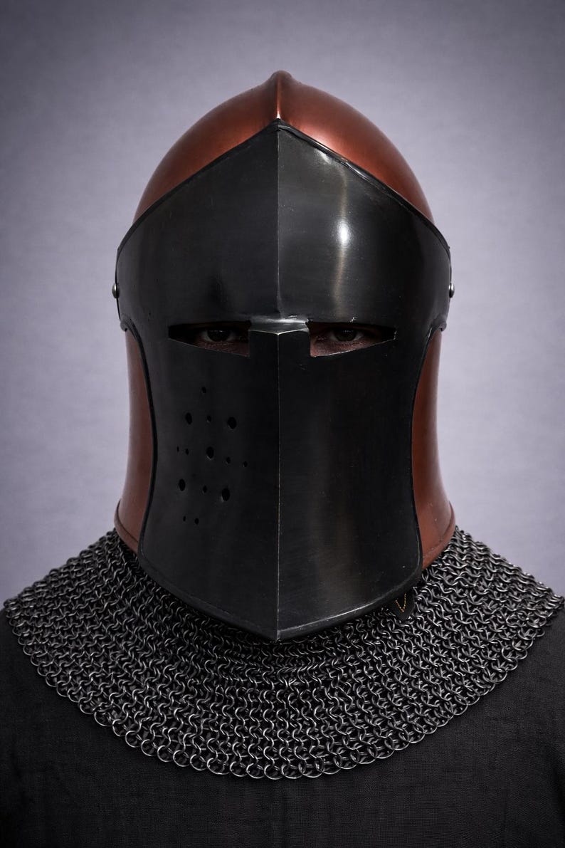 May include: A medieval knight's helmet with a black visor and a copper-colored top. The helmet has a series of small holes on the visor and is paired with a chainmail collar. The background is a solid, light purple color.