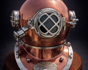 May include: A vintage copper diving helmet with a polished finish, mounted on a wooden base. The helmet features a round, riveted design with a front viewing window, side portholes, and a top vent. A metal plaque is affixed to the wooden base.