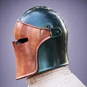 Puede incluir: Un casco medieval con una corona verde oscuro y una protecci&oacute;n facial de color cobre. El casco tiene una visera con bisagras y un detalle de cadena. El fondo es de color p&uacute;rpura suave.