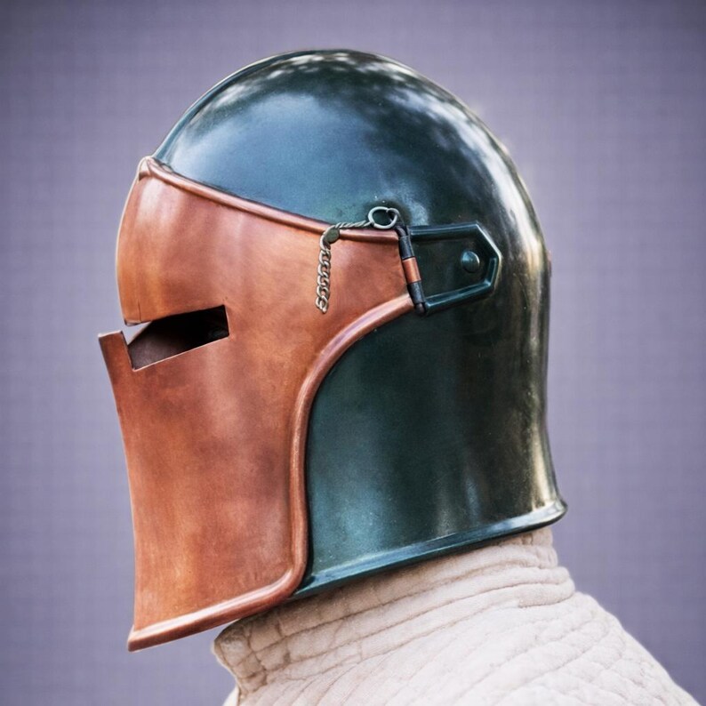 Puede incluir: Un casco medieval con una corona verde oscuro y una protecci&oacute;n facial de color cobre. El casco tiene una visera con bisagras y un detalle de cadena. El fondo es de color p&uacute;rpura suave.