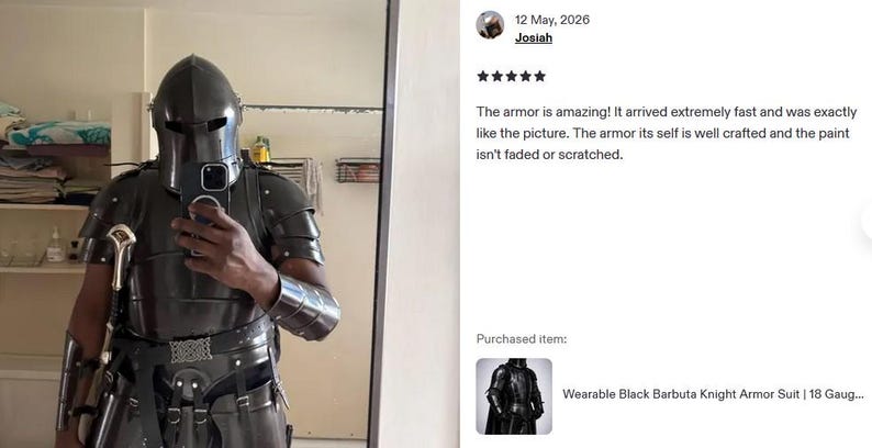 May include: A person wearing a black knight armor suit, including a helmet, chest plate, and arm guards. The armor has a metallic sheen and is detailed with rivets and straps. The suit is designed to be wearable.