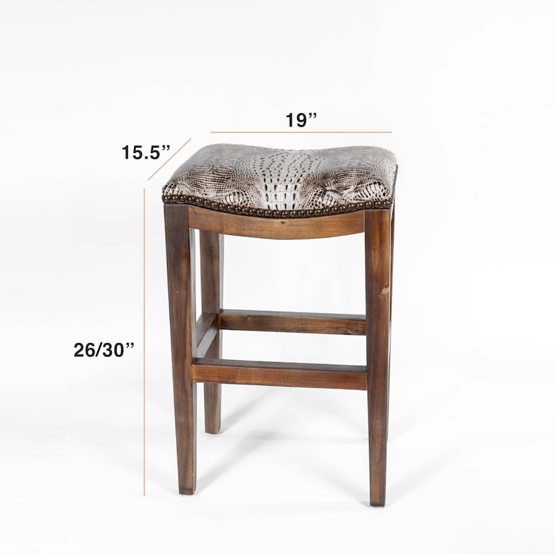 Pode incluir: Banqueta de bar de madeira com assento em pele de cobra sint&eacute;tica. O assento mede 48 cm de largura e 39 cm de profundidade. A altura da banqueta &eacute; de 66/76 cm. A estrutura &eacute; de madeira castanha escura.