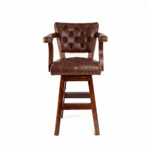 May include: A brown leather bar stool with a tufted back and seat, featuring armrests and a wooden frame. The stool has a swivel function and is approximately 40 inches tall.