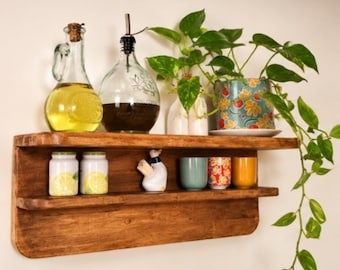 May include: A two-tiered wooden wall shelf holding two glass bottles with liquid, a potted plant with green leaves, two small jars with lemon graphics, a white duck-shaped figurine, and three small cups in light blue, floral, and yellow.