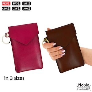 May include: Two leather phone cases, one burgundy and one brown, with a flap closure and a gold-colored keyring. The burgundy case is on the left, and the brown case is held by a hand on the right. The text "in 3 sizes" is below the burgundy case.
