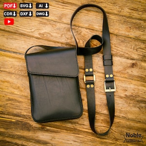 Puede incluir: Bolso bandolera de cuero negro con cierre de solapa y correa ajustable. El bolso presenta hebillas doradas y se exhibe sobre una superficie de madera. El bolso es de Noble Leather Art.