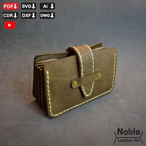 May include: A brown leather card holder with white stitching and a strap closure. The card holder has a rectangular shape and a brass-coloured button clasp. The text "Noble Leather Art" is in the bottom right corner.