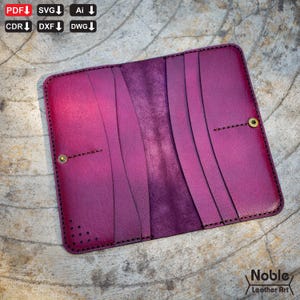 Peut inclure: Portefeuille en cuir magenta ouvert, avec plusieurs fentes pour cartes et une fermeture à bouton-pression. L'intérieur est violet foncé et cousu avec du fil noir. Les bords sont arrondis, et le portefeuille est présenté ouvert. Le texte "Noble Leather Art" est visible.