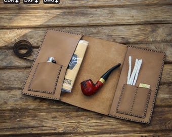 May include: A brown leather tobacco pipe case with a pipe, lighter, and cleaning supplies. The case is open, revealing pockets for accessories. The pipe is red and black. The case has the words "Noble Leather Art" on the bottom right.