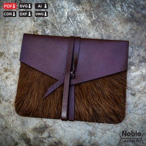 May include: A handcrafted leather wallet with a distinctive look. The top flap is a deep burgundy hue, contrasting with the brown fur on the lower section. A leather strap secures the wallet. The words "Noble Leather Art" are visible in the bottom right corner.