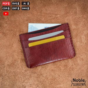 May include: A burgundy leather cardholder with multiple slots, holding a bill and two cards. The cardholder is made of textured leather and has a stitched border. The logo "Noble Leather Art" is visible in the bottom right corner.