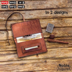 Può includere: Un astuccio per tabacco in pelle marrone con un cinturino, aperto per rivelare tabacco e un accendino. L'accendino è argentato con la scritta "NAVY". È visibile anche una pipa di legno intagliato. Il testo "In 2 designs" è in alto a destra.