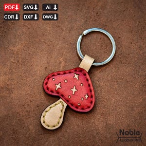 以下が含まれることがあります： 赤い革製のキノコのキーホルダー。白い星のアクセントとベージュの茎が付いています。キーホルダーにはシルバーのリングとベージュの革のループが付いています。画像には「PDF、SVG、AI、CDR、DXF、DWG」と「Noble Leather Art」の文字も含まれています。