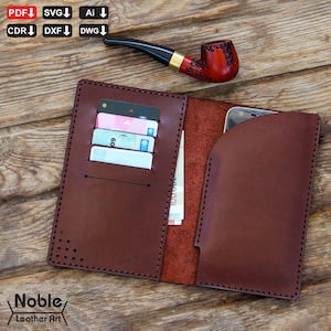 May include: Open brown leather wallet with card slots and a phone pocket. The wallet is open, revealing cards and cash. A red and black pipe rests on the wooden surface. The wallet has the text "Noble Leather Art".