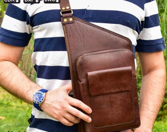 Peut inclure: Sac bandoulière en cuir marron avec une poche avant et une bandoulière réglable. Le sac est porté en travers du corps. Le sac porte le texte "Noble Leather Art" en bas à gauche.