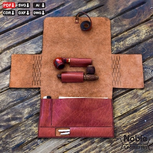 Könnte beinhalten: Offene Tabakpfeifentasche aus Leder in Braun- und Rottönen. Die Tasche enthält zwei Pfeifen, jeweils in einer schützenden Lederhülle. Die Tasche ist offen und zeigt eine Tasche und einen Schlaufenverschluss. Das Logo "Noble Leather Art" ist sichtbar.
