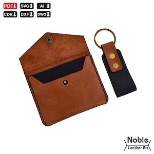 Puede incluir: Una cartera de cuero marrón con cierre de botón a presión e interior negro, junto a un llavero de cuero negro y marrón a juego con un anillo de latón. La cartera está abierta. El logotipo "Noble Leather Art" está en la esquina inferior derecha.